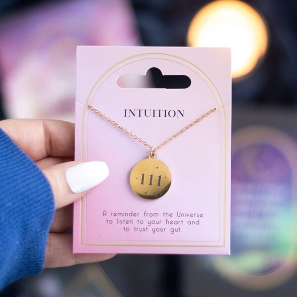 A gold necklace with the inscription "111" on a pink card labeled "INTUITION."