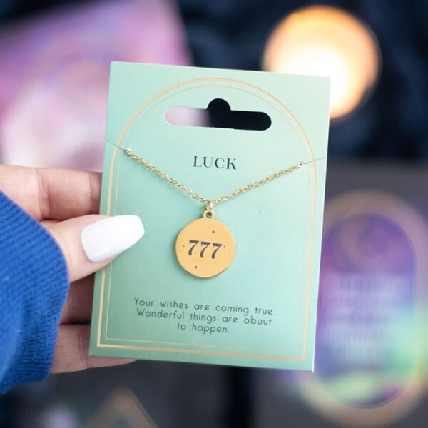 A hand holding a golden 777 necklace on a card stating "Luck" with a motivational message.