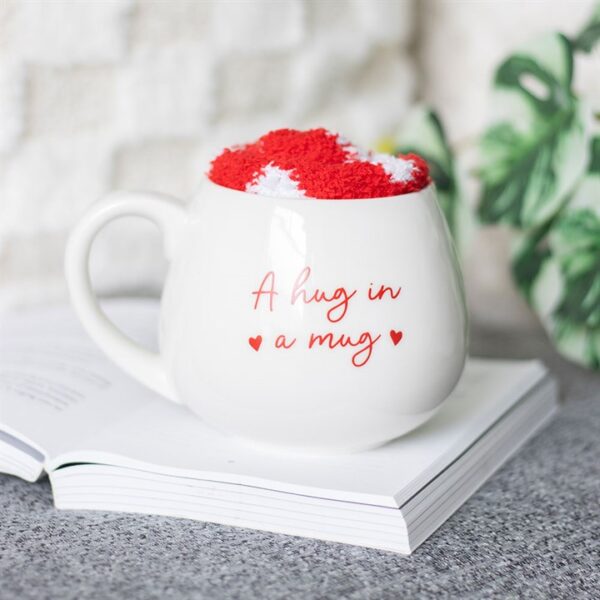 A whimsical white mug filled with red and white fluff, resting on an open book.