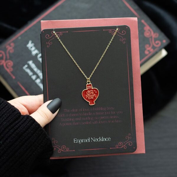 A red enamel love potion necklace displayed on a card, emphasizing its romantic significance and charm. 1740513728.